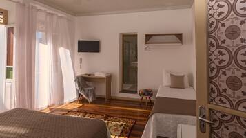 Habitación de hotel con dos camas, un escritorio, una silla, un televisor y un baño visible a través de una puerta abierta.