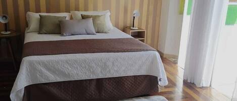 A bedroom with a bed, bedside tables, a lamp, and a patterned rug.