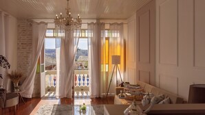 A spacious living room with a chandelier, a sofa set, and a view of a balcony with a railing. - Hotel Canto Do Chafariz (Diamantina)