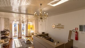 A hotel reception area with a chandelier, a reception desk, a fire extinguisher, and a sign indicating the hotel name. - Hotel Canto Do Chafariz (Diamantina)