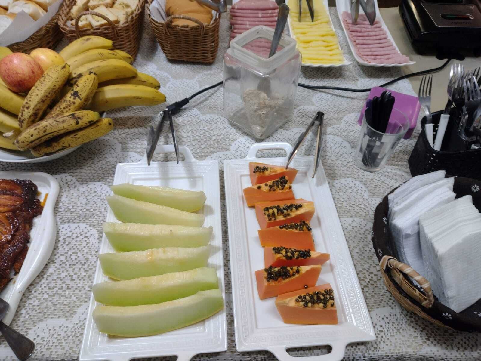A buffet table with various food items including bananas, apples, and sliced fruits.
