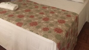 Un dormitorio con cama, cabecera, mesita de noche y una obra de arte colgada en la pared.