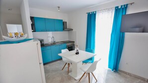 Una cocina moderna con armarios azules, una mesa de comedor blanca y un televisor de pantalla plana.