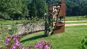 A garden with a stone wall, a wooden structure, and purple flowers. - Spacious Schneiderhof vacation apartment with terrace (Neukirchen)