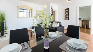 A dining area with a glass table, black chairs, white plates, and a vase with flowers. - Spacious Apartment "Casa Nancy" with Mountain View, Pool, Wi-Fi & Terrace (Yaiza)