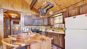 Una cocina rústica con gabinetes de madera, una isla central, una estufa y un refrigerador.