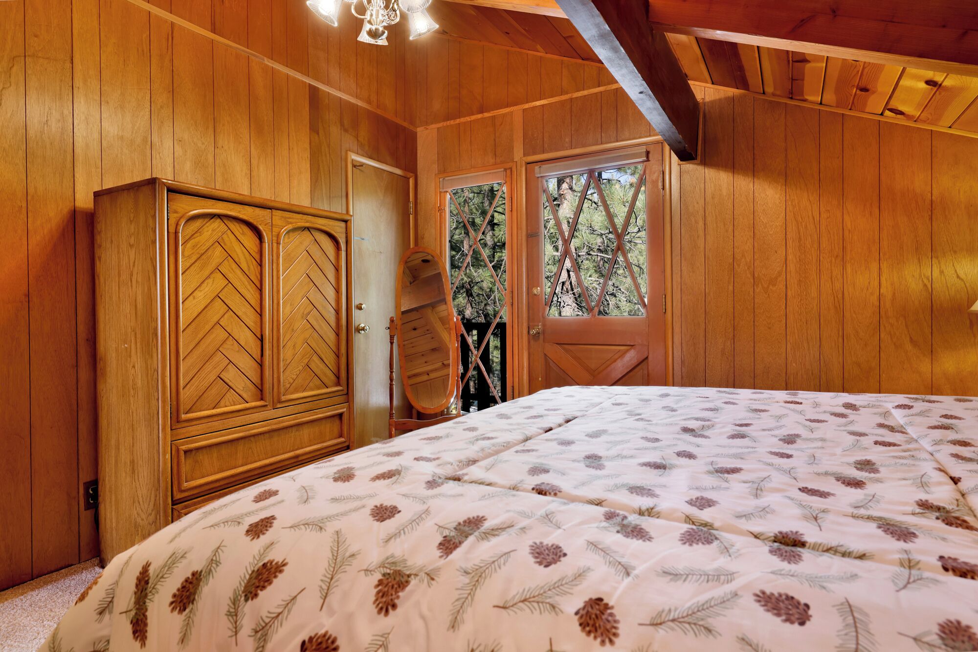 Une pièce en bois avec un lit, une armoire et une porte donnant sur un balcon.