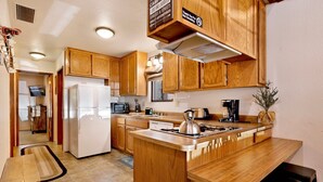 Une cuisine avec des meubles de rangement en bois, un réfrigérateur, un four à micro-ondes, une cuisinière et un évier.