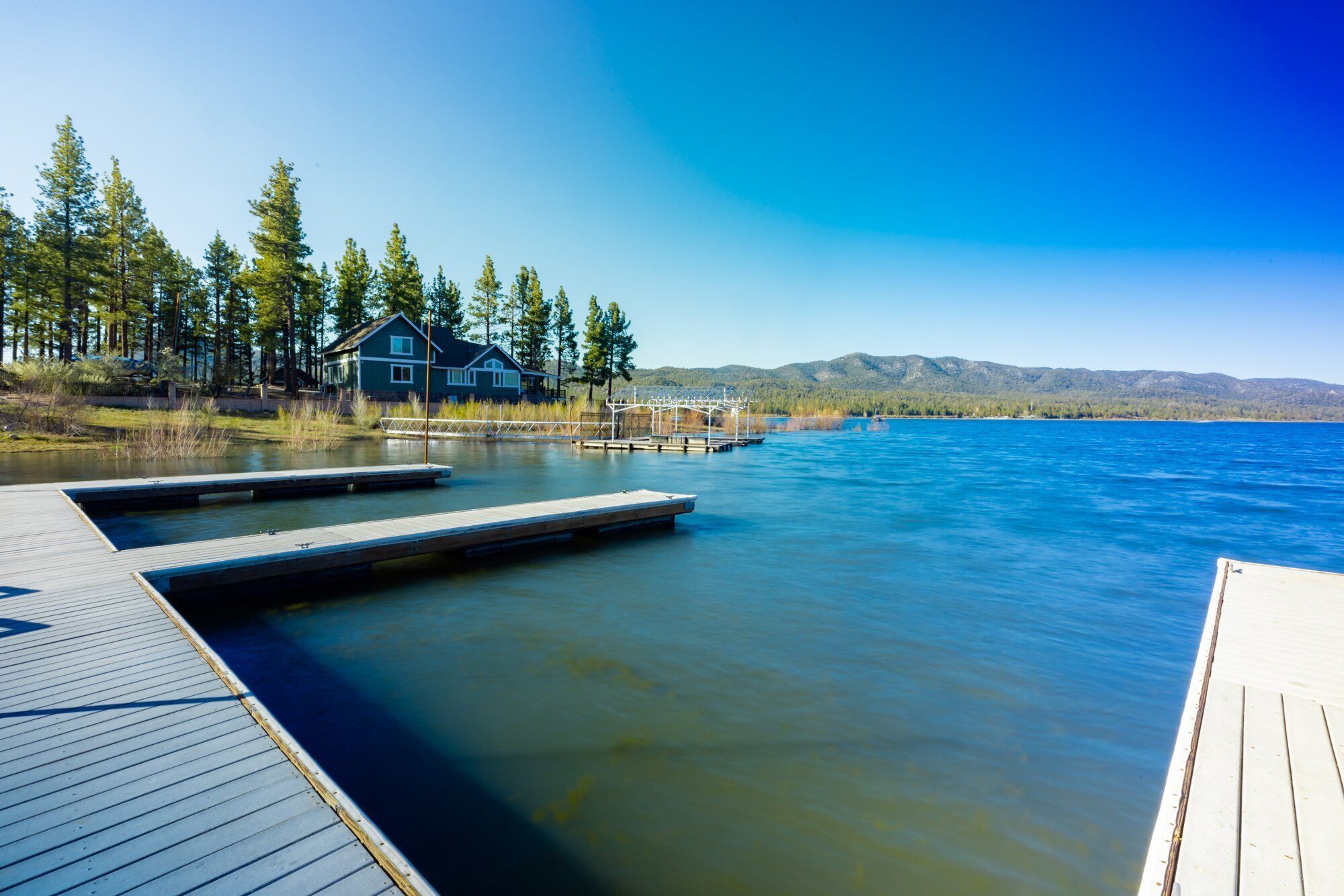 A lakeside property with a dock extending into the water, surrounded by trees and a house.