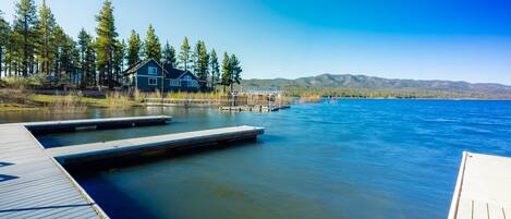 A lakeside property with a dock extending into the water, surrounded by trees and a house.