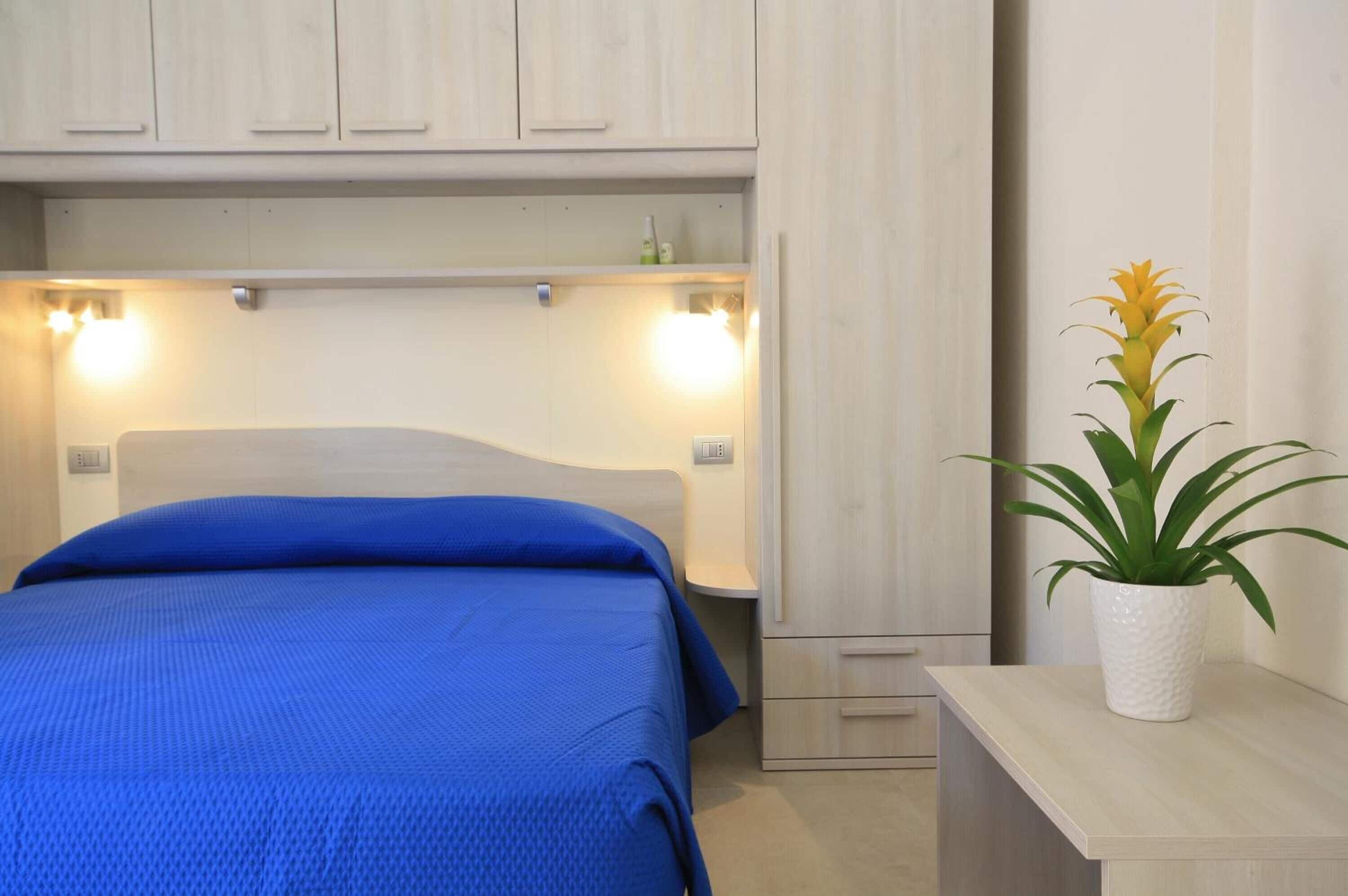 Ein Schlafzimmer mit einem Bett, Nachttischlampen, einem Beistelltisch und einer Topfpflanze.