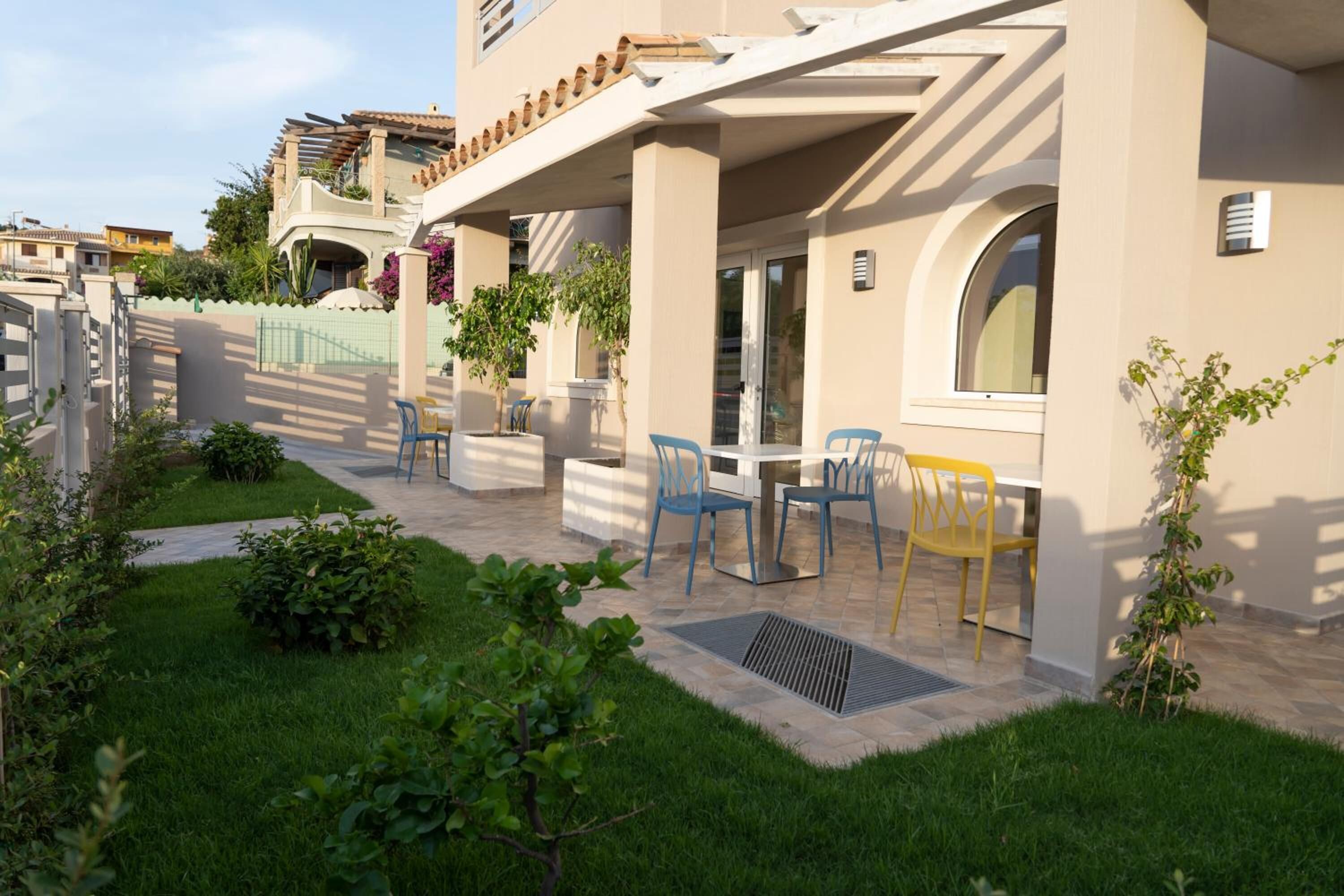 Un edificio residencial con un patio cubierto, mobiliario exterior y un jardín bien cuidado.