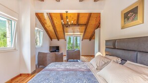 Ein Schlafzimmer mit einem großen Bett, einem Fernseher, einem Sessel und einem Balkon mit Blick.