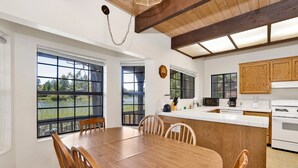 A modern kitchen with a wooden island, large windows, and a view of a lake.
