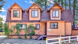 A wooden cabin with a steeply pitched roof, multiple windows, and a small porch.