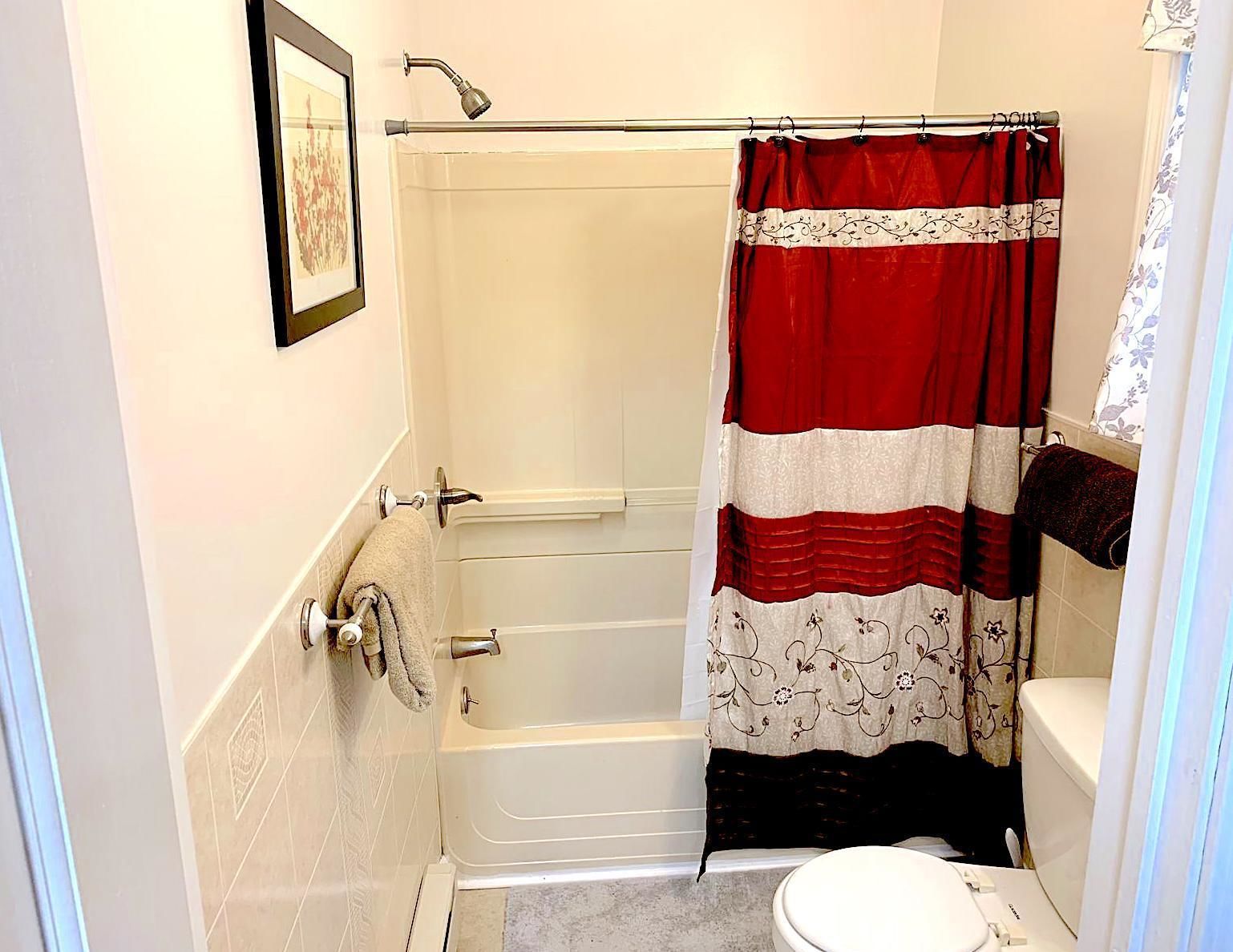 Une salle de bain avec une baignoire, des toilettes et un rideau de douche.