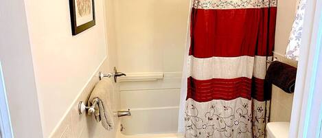 Une salle de bain avec une baignoire, des toilettes et un rideau de douche.
