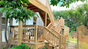 A wooden deck with a staircase leading to a covered porch.