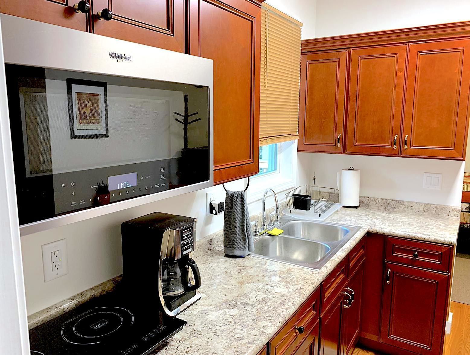 A kitchen with wooden cabinets, a built-in microwave, a coffee maker, and a sink.