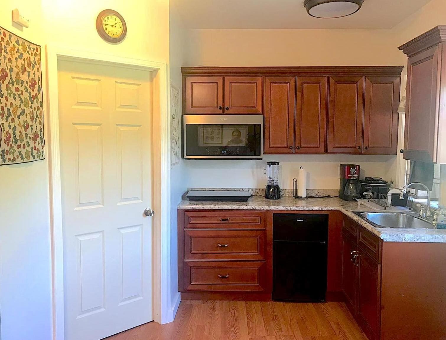 Una cocina compacta con armarios de madera, un microondas, una cafetera y un lavavajillas.