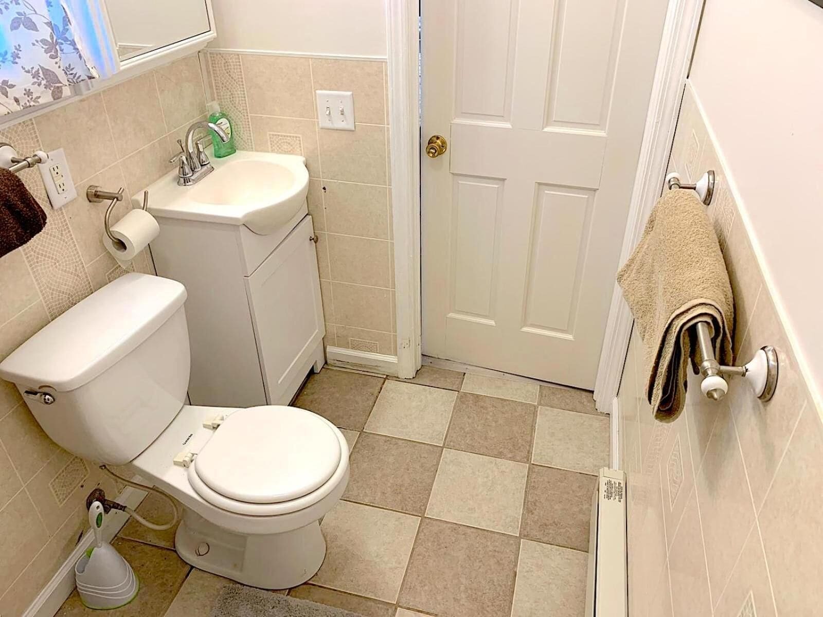 A bathroom with a toilet, sink, and a towel rack.