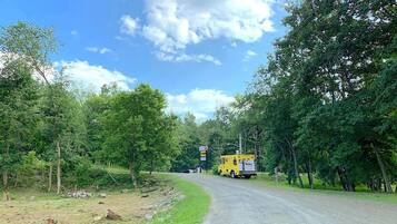 Uma estrada rural com um caminhão amarelo estacionado na lateral.