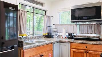 A kitchen with granite countertops, wooden cabinets, a stainless steel refrigerator, a microwave, and a coffee maker.