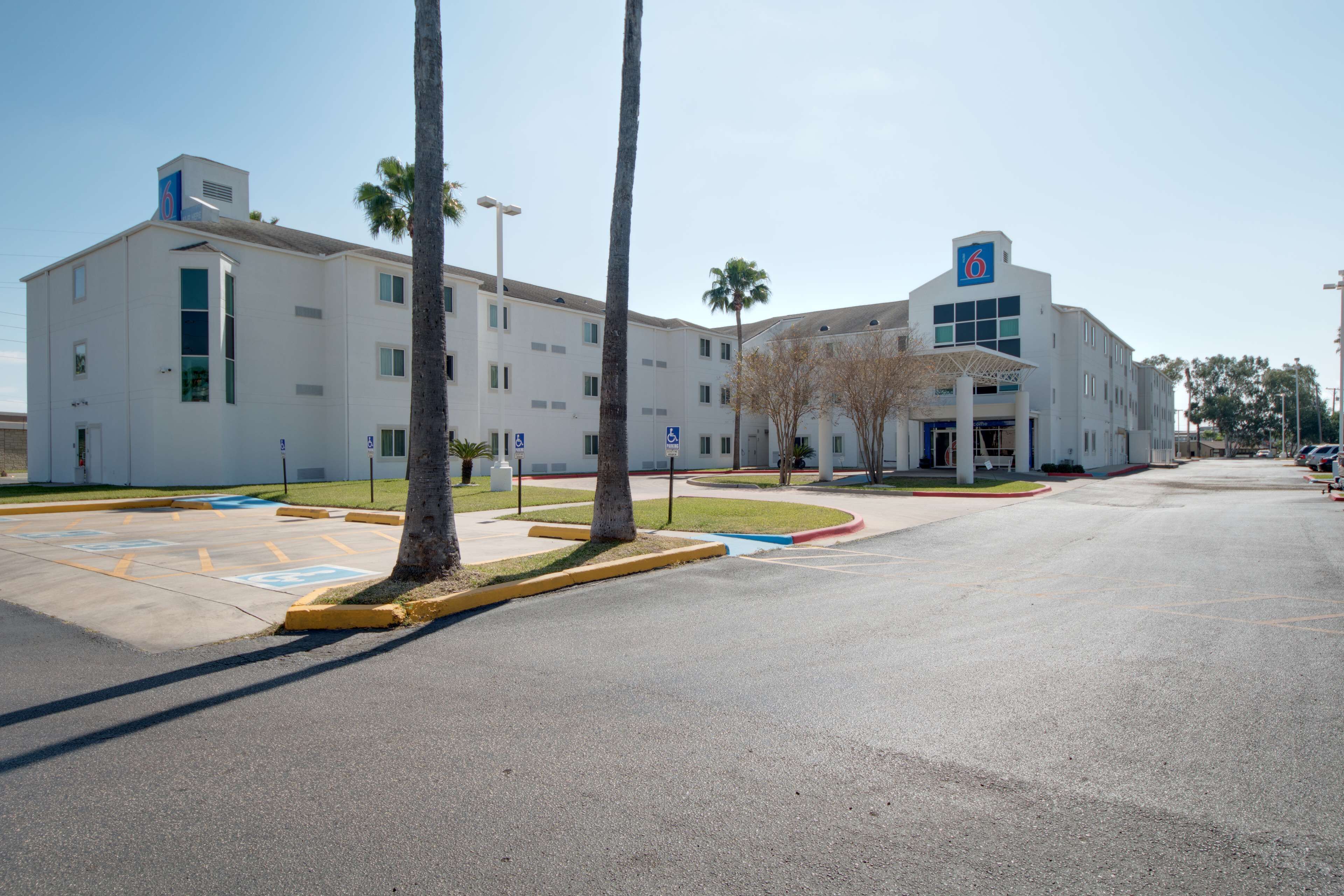 A modern building with a flat roof, multiple windows, and a parking lot with marked handicapped spaces.