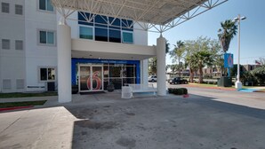 Entrada de hotel con toldo azul, un cartel con el número 6 y una zona de estacionamiento techada.