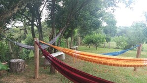 A hammock set up between trees in a grassy area with a bench nearby. - Pousada Dedo de Deus (Paraisopolis)