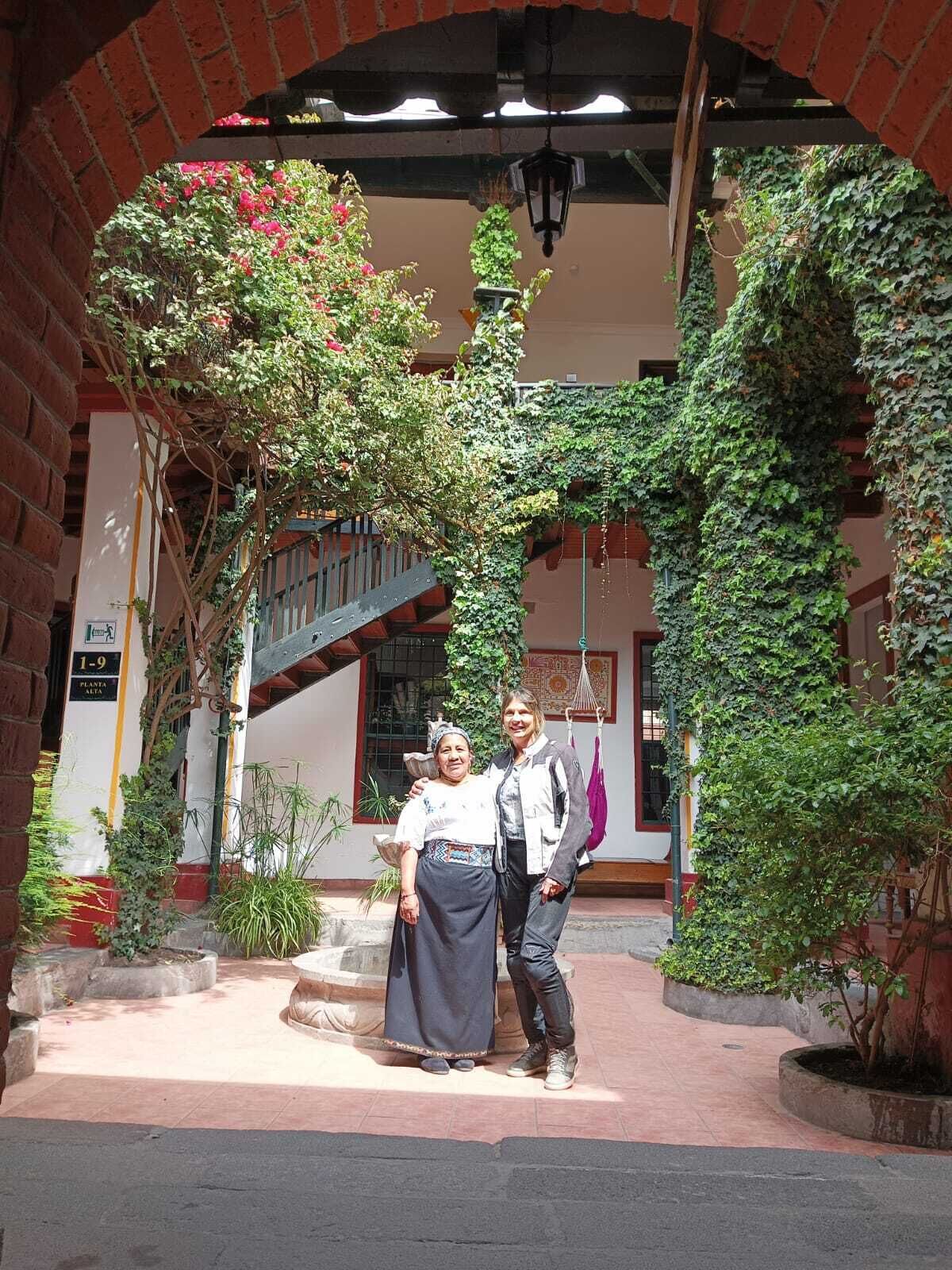 Un patio interior con arcos de ladrillo, una escalera y abundante vegetación.