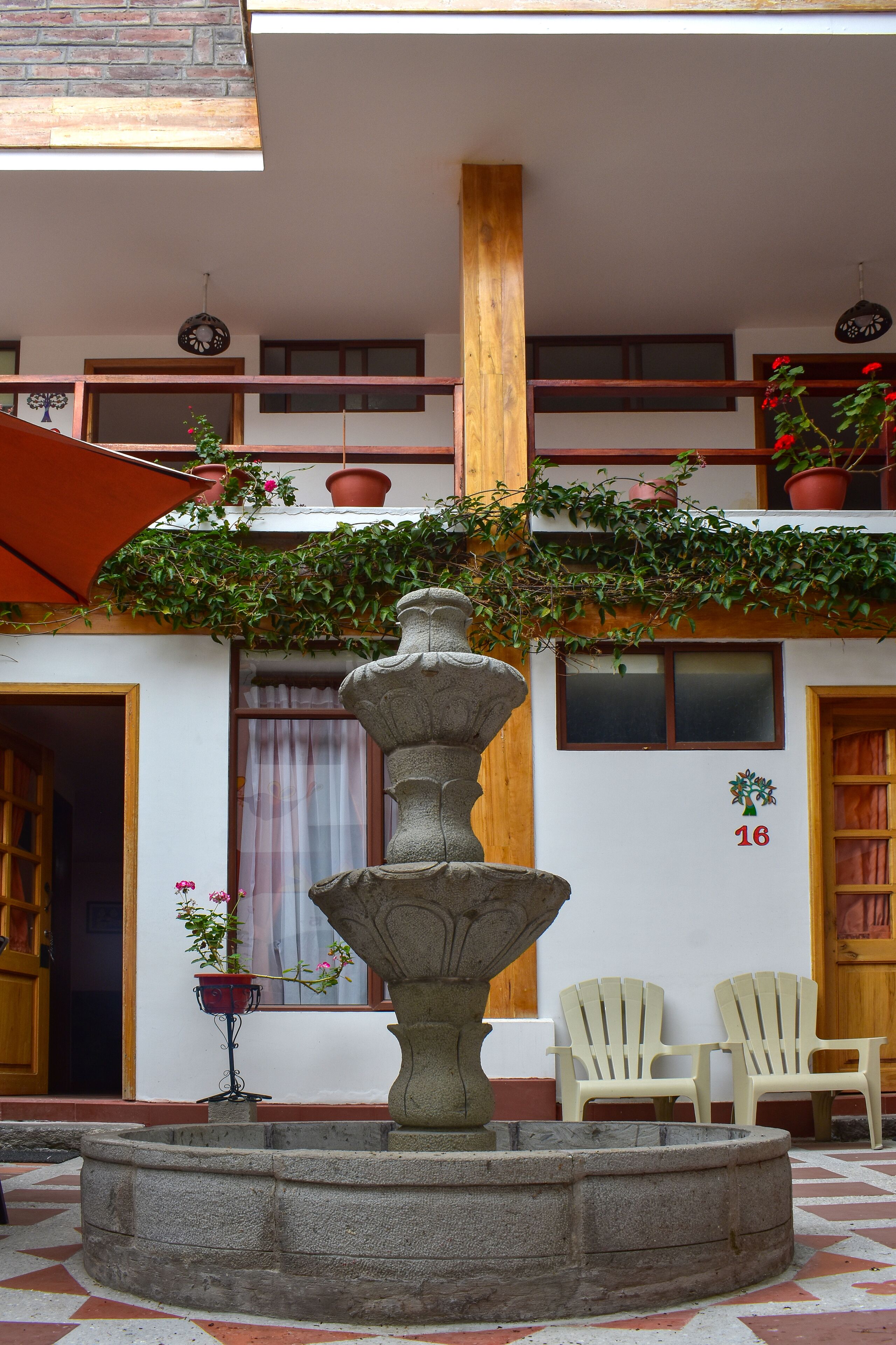 A courtyard with a stone fountain, two chairs, and a wooden door.