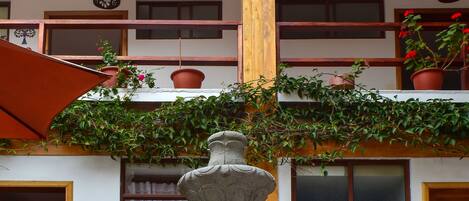 A courtyard with a stone fountain, two chairs, and a wooden door.