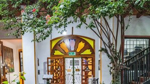 A courtyard with a central fountain, surrounded by greenery and a building entrance with a decorative archway. - Hostal Riviera Sucre (Otavalo)