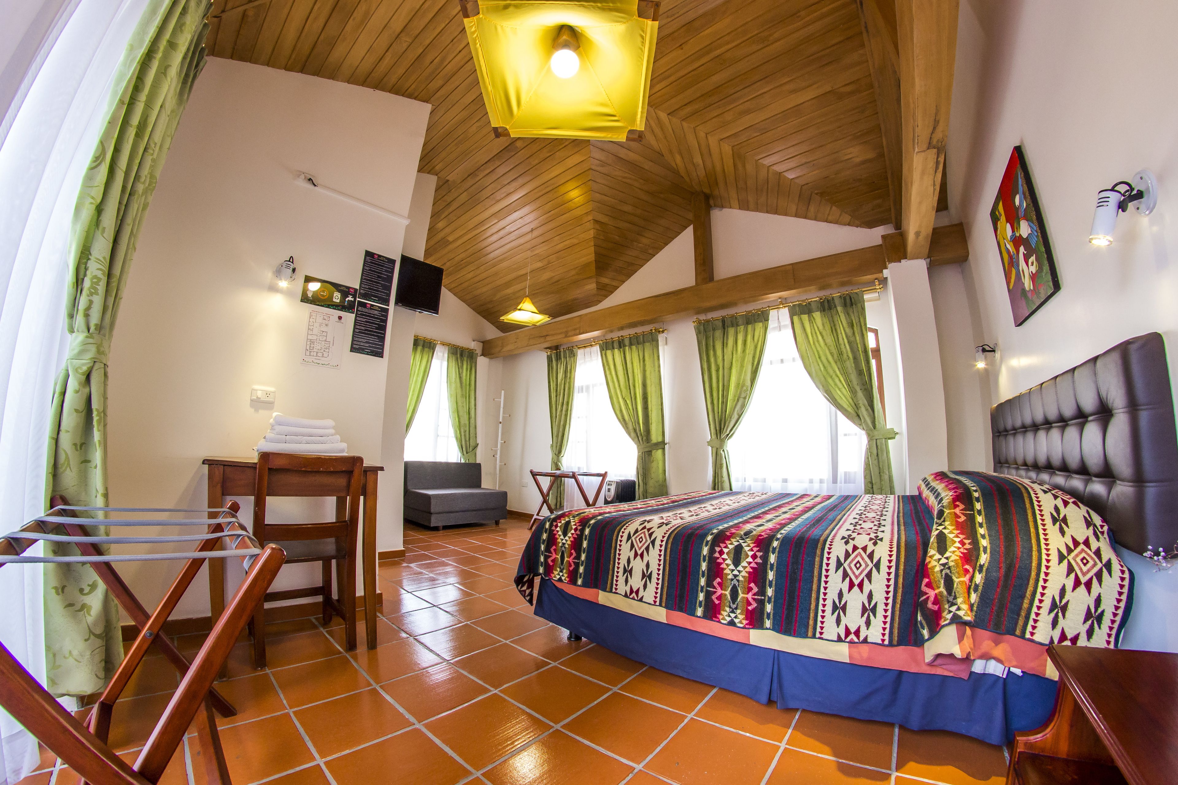 Ein Schlafzimmer mit einem großen Bett, einer Holzbalkendecke und grünen Vorhängen.