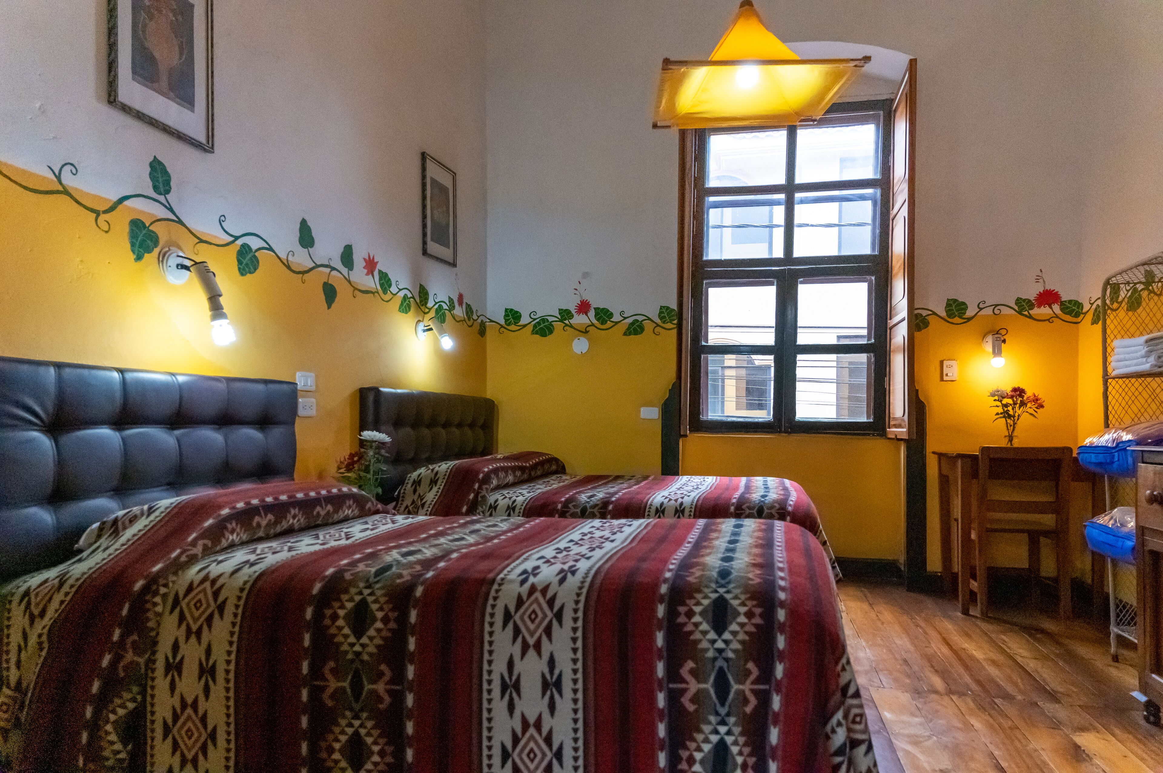 A room with two beds, a window, a chair, and a table.
