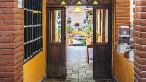 An arched brick corridor with a yellow wall and a wooden door. - Hostal Riviera Sucre (Otavalo)