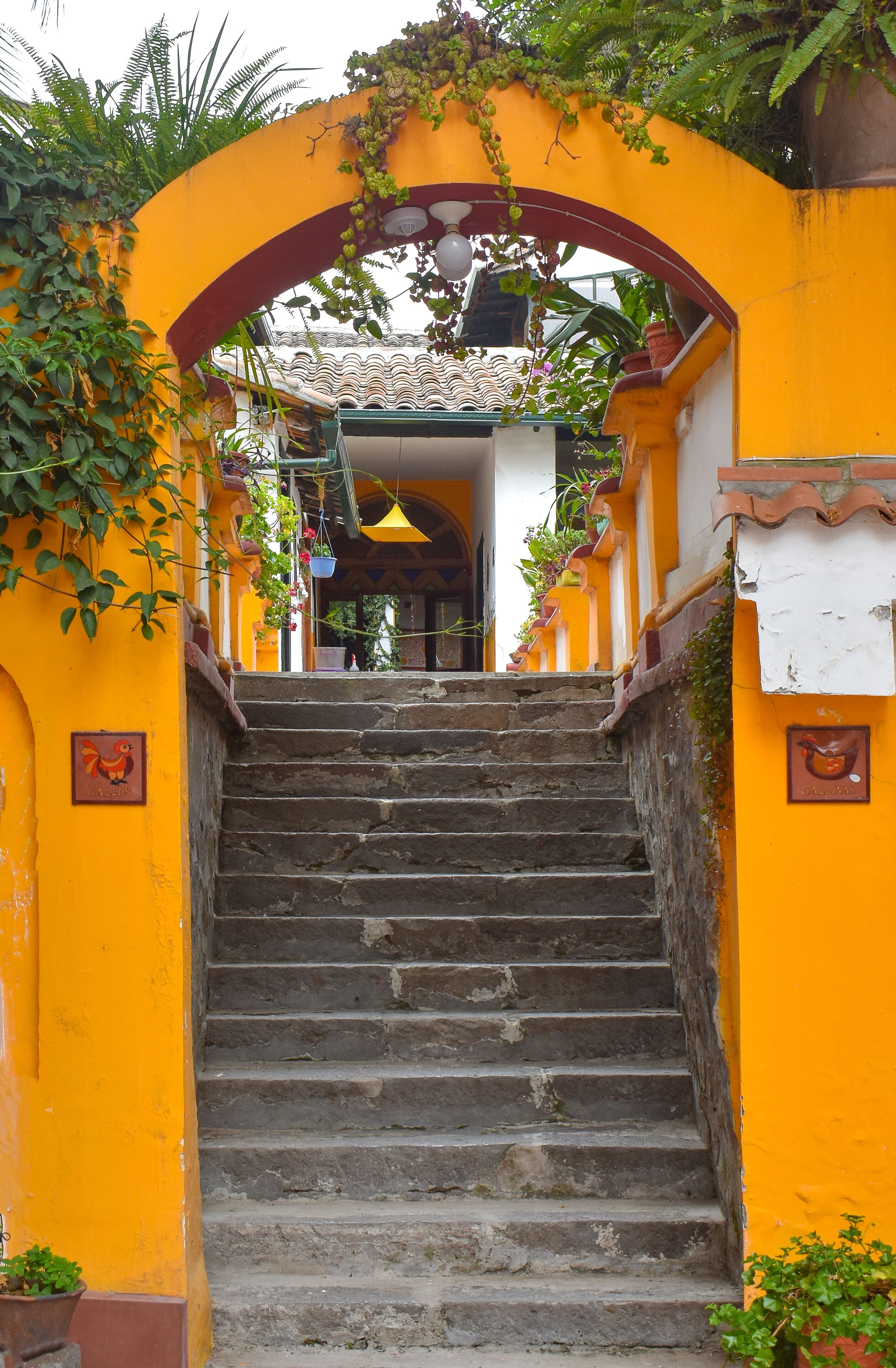 A staircase leading to a building with a yellow facade and a tiled roof.