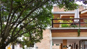 A courtyard with a tiled floor, a wooden archway, and potted plants. - Hostal Riviera Sucre (Otavalo)