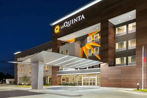 A modern hotel with a prominent 'La Quinta' sign, featuring a covered entrance and a well-lit facade. - La Quinta Inn & Suites by Wyndham College Station North (College Station)