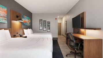Una habitación de hotel con una cama grande, un escritorio con silla, un televisor y obras de arte en las paredes.
