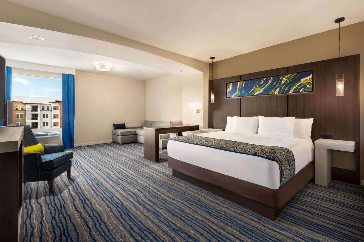 Habitación de hotel con una cama grande, un escritorio, una silla y vistas a edificios.