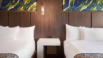 A hotel room with two beds, a bedside table, and a wall-mounted light fixture.