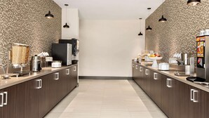 Una cocina moderna con armarios de madera oscura, electrodomésticos de acero inoxidable e iluminación colgante.