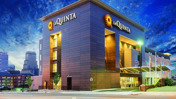 Un hotel moderno con la señalización de "La Quinta", que cuenta con una entrada destacada y un área exterior cubierta.