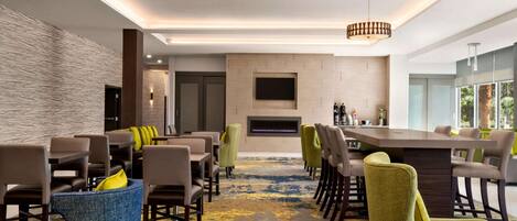 A modern dining area with a long table, multiple chairs, and a central fireplace.