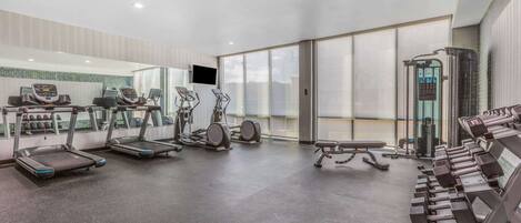 A modern gym with treadmills, elliptical machines, and weight benches.