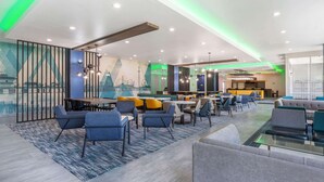 Un moderno hall de hotel con comedor, arreglos de asientos y un mural en la pared.