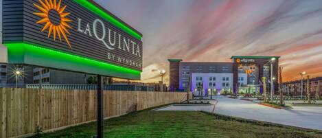 Un hotel llamado La Quinta by Wyndham con un letrero llamativo, un césped bien cuidado y un estacionamiento.