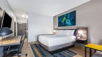 A hotel room with a bed, desk, chair, nightstands, and a painting on the wall.
